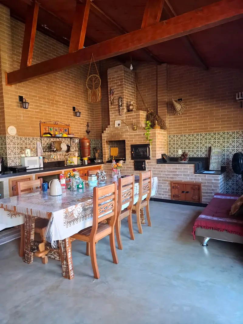 Copa e cozinha da Cabana Lua com fogão a lenha de tijolos e mesa de madeira para seis lugares