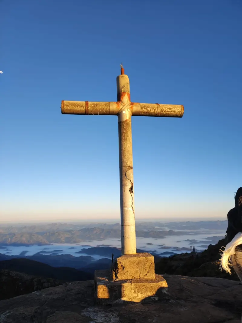Cruzeiro de metal no cume do Pico da Bandeira acima do mar de nuvens